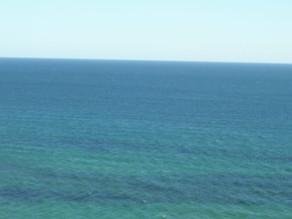 Vast ocean under a clear sky with a watermark at the bottom right