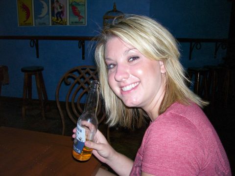 1991 Ford Bronco - A woman smiles while holding a beer bottle in a dimly lit bar with artwork on the wall.