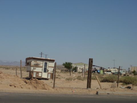 1991 Ford Bronco - A remote desert location features a small, makeshift dwelling on a sandy patch, with a clear blue sky overhead.