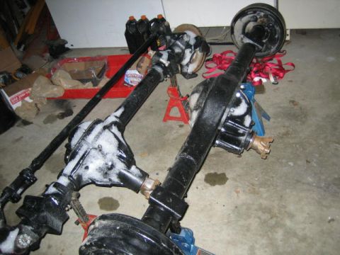1978 Ford Bronco - Vehicle axles are shown in a garage setting, covered in a white substance and supported by jack stands.