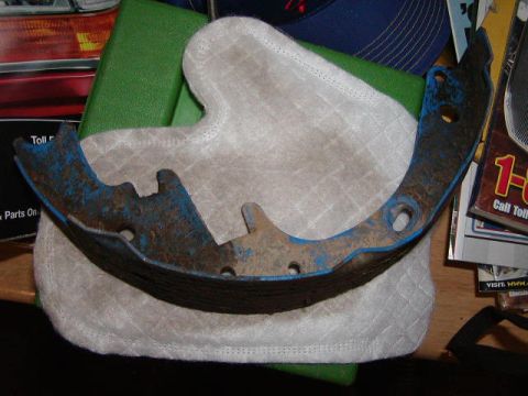 1978 Ford Bronco - A single brake shoe, showing signs of wear and rust, rests on a quilted fabric pad.
