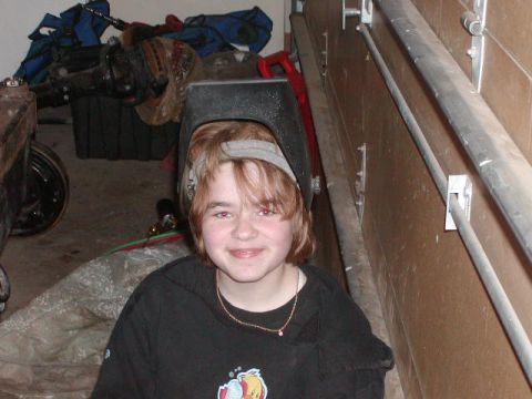1978 Ford Bronco - A young person wearing a welding mask smiles for the camera in a cluttered garage setting.
