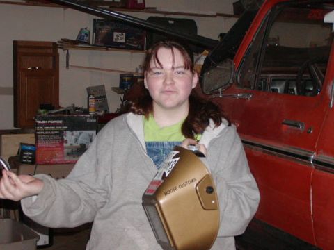 1978 Ford Bronco - A person holds a welding mask in a garage, with a red vehicle partially visible in the background.
