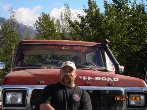 1978 Ford Bronco - A man stands in front of a red Ford truck with "OFF-ROAD" written on the hood.