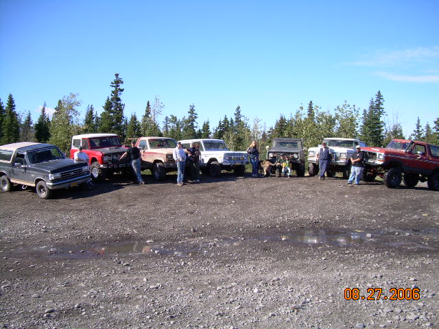 Group of 1978 Ford Broncos parked on gravel lot, trees in background