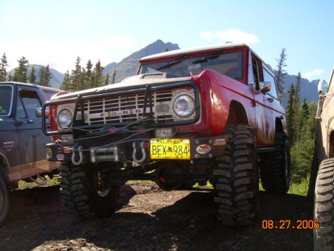1978 Ford Bronco - This red 1978 Ford Bronco is equipped with large off-road tires and a front winch, parked next to another vehicle.