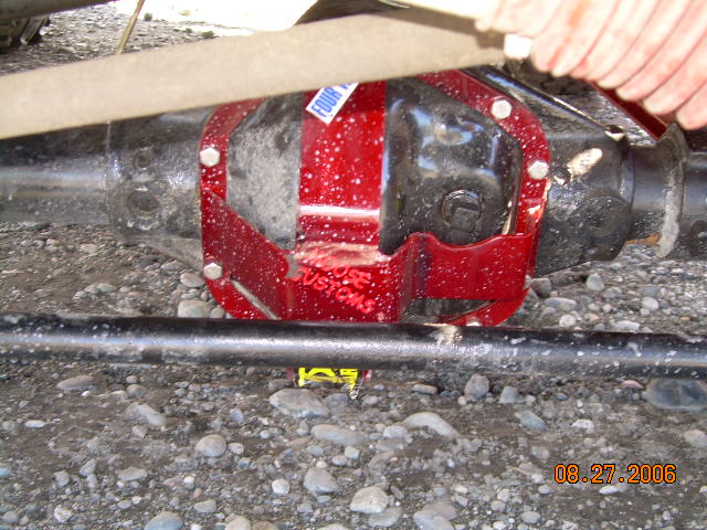 red aftermarket differential cover bolted onto a vehicle's rear axle