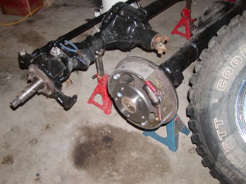 1978 Ford Bronco - Vehicle axles and brake components are disassembled and supported by jack stands on a garage floor.