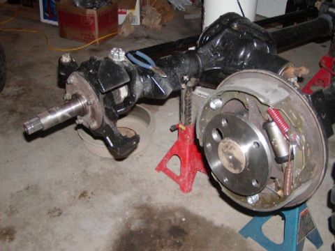 1978 Ford Bronco - Close-up of a vehicle's rear axle and brake components, resting on jack stands.