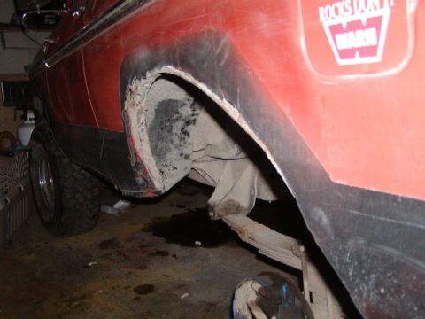 1978 Ford Bronco - The rear wheel well of a red 1978 Ford Bronco shows significant rust and body damage.