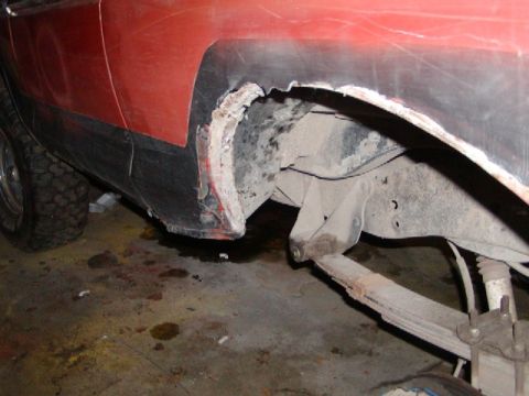 1978 Ford Bronco - Close-up view of significant rust and damage to the rear wheel well and suspension components of a vehicle.