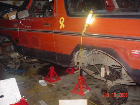 1978 Ford Bronco - This orange SUV is undergoing repairs, with its rear wheel off and supported by jack stands.