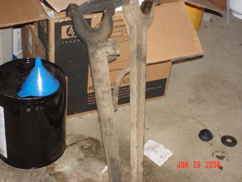 1978 Ford Bronco - Two dusty metal automotive parts are shown in a garage setting with cardboard boxes and a blue funnel.