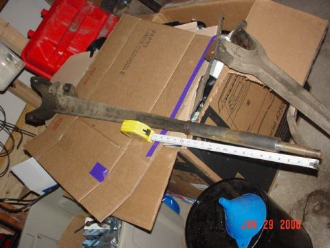 1978 Ford Bronco - A metal automotive part, possibly a steering linkage, is shown with a measuring tape.