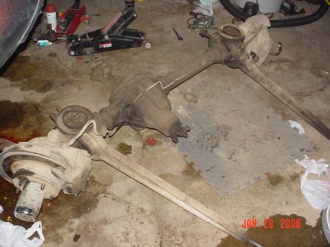 1978 Ford Bronco - Two vehicle axles and differentials are shown on a garage floor.