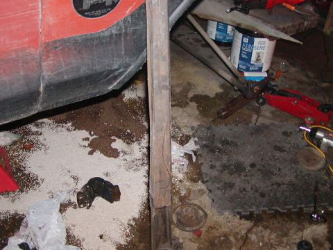 1978 Ford Bronco - A partial view of a red vehicle's fender is visible, resting on a cluttered workshop floor.