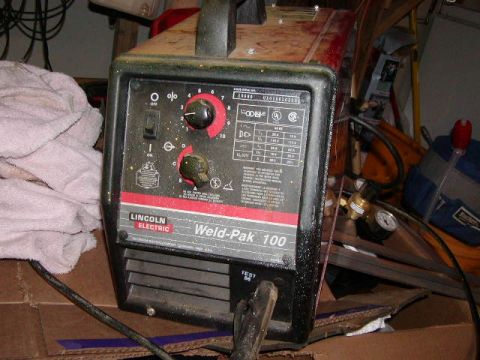 1978 Ford Bronco - A Lincoln Electric Weld-Pak 100 welder sits on a cardboard box in a cluttered garage.