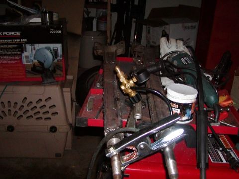 1978 Ford Bronco - Welding equipment, including a torch, pressure gauge, and clamps, is arranged on a workbench in a cluttered garage.