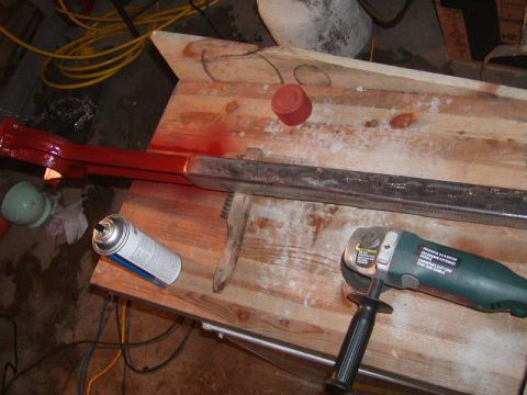 1978 Ford Bronco - A metal bar is being painted red on a workbench with tools nearby.