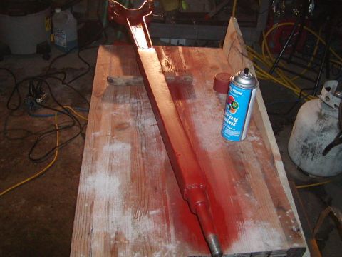 1978 Ford Bronco - A red painted metal part rests on a wooden workbench next to a can of spray paint.