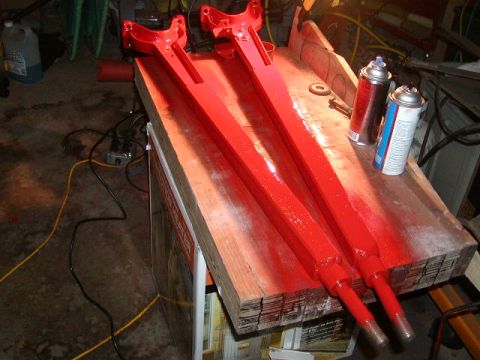 1978 Ford Bronco - Red painted metal parts sit on a workbench next to spray cans, likely awaiting installation.