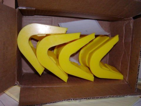 1978 Ford Bronco - A cardboard box holds multiple yellow, curved plastic components, possibly for automotive use.