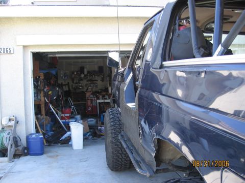 1994 Ford Bronco - 1994 Ford Bronco with its half doors removed, parked outside a garage.