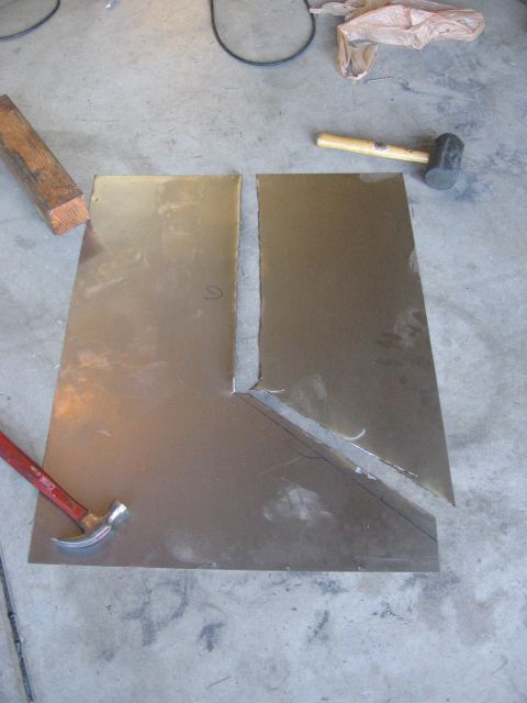 1994 Ford Bronco - A metal sheet has been cut into two pieces, with tools like hammers and a wood block nearby on a concrete surface.