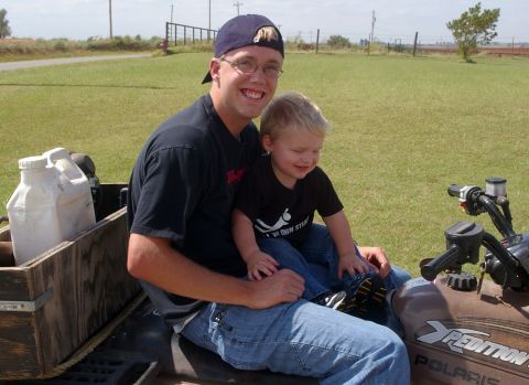 1998 Jeep TJ - A man and a young child sit on an ATV, smiling for the camera.