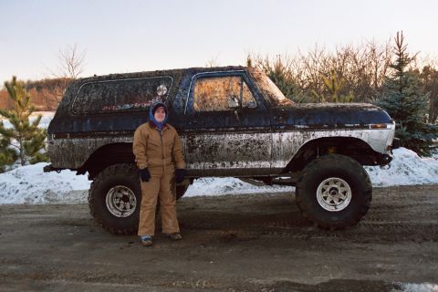 1979 Ford Bronco - A muddy 1979 Ford Bronco is parked in the snow with a person standing next to it.