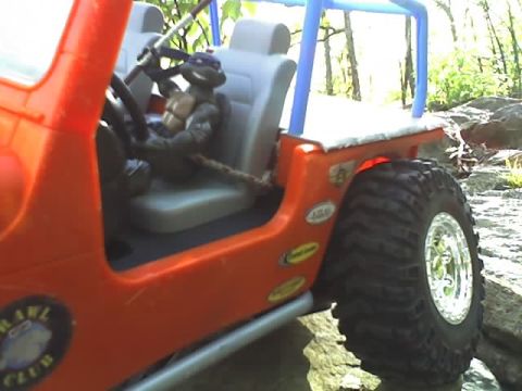 1976 GMC C/K Pickup - This orange jeep, modified for off-roading, features a Teenage Mutant Ninja Turtle at the wheel and a blue roll cage.