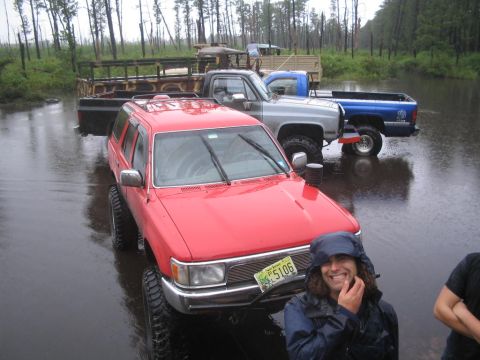 1990 Ford Bronco - Several off-road vehicles are submerged in water, with a red SUV in the foreground.