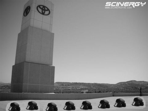 1993 Ford Taurus - A Toyota dealership tower stands tall against the sky, with several individuals kneeling on the ground in front of it.