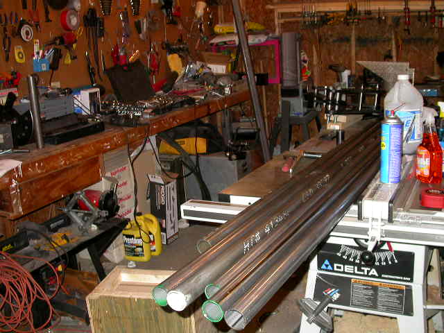 Long lengths of round steel tubing laid across a Delta table saw in a home garage shop