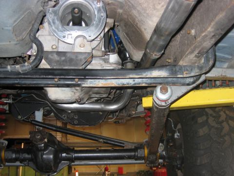 1992 Ford Bronco - Underside view of a lifted 4x4 showing the front differential, driveshaft, coil springs with red shocks, black sway bar/track bar, exhaust…