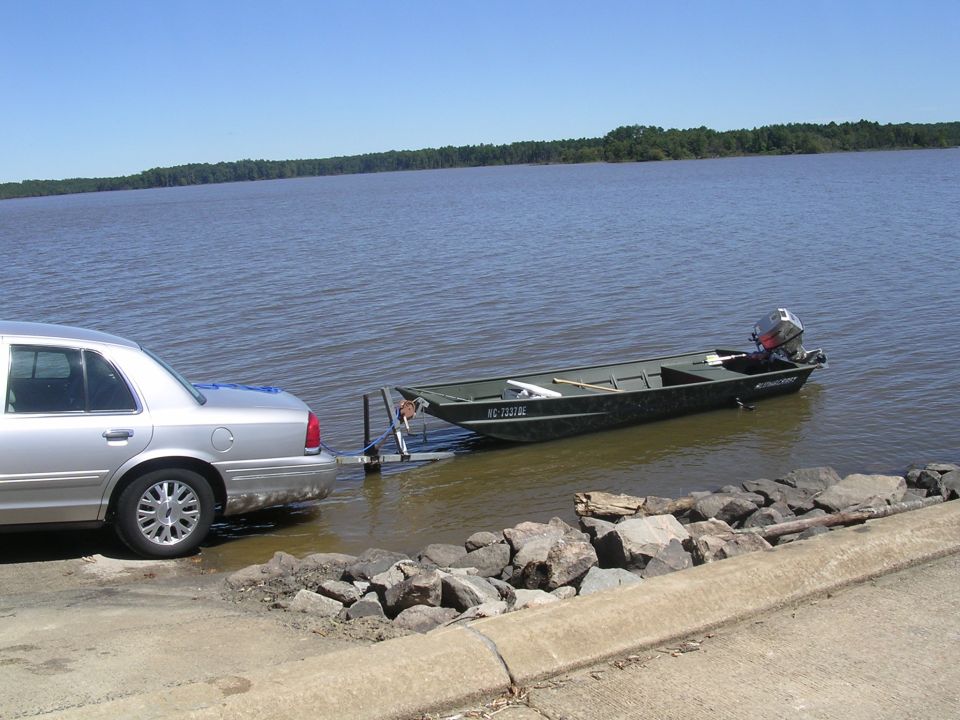 Silver sedan launching a jon boat at a lake ramp