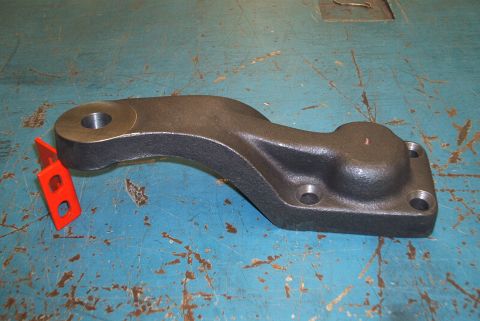 1983 Ford Bronco - A dark metal steering arm with a red tag is shown against a blue, worn surface.