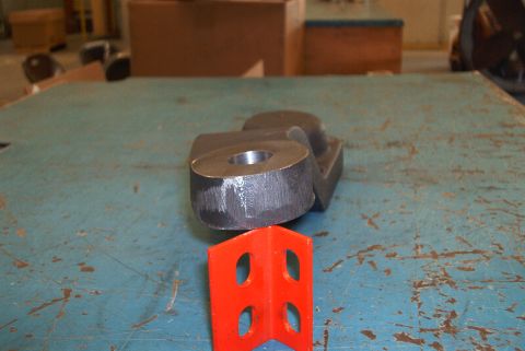 1983 Ford Bronco - Metal steering arm part shown on an orange bracket, likely in a workshop setting.