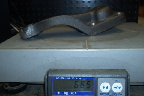 1983 Ford Bronco - A metal steering arm part is weighed on a digital scale, displaying 6.65 pounds.