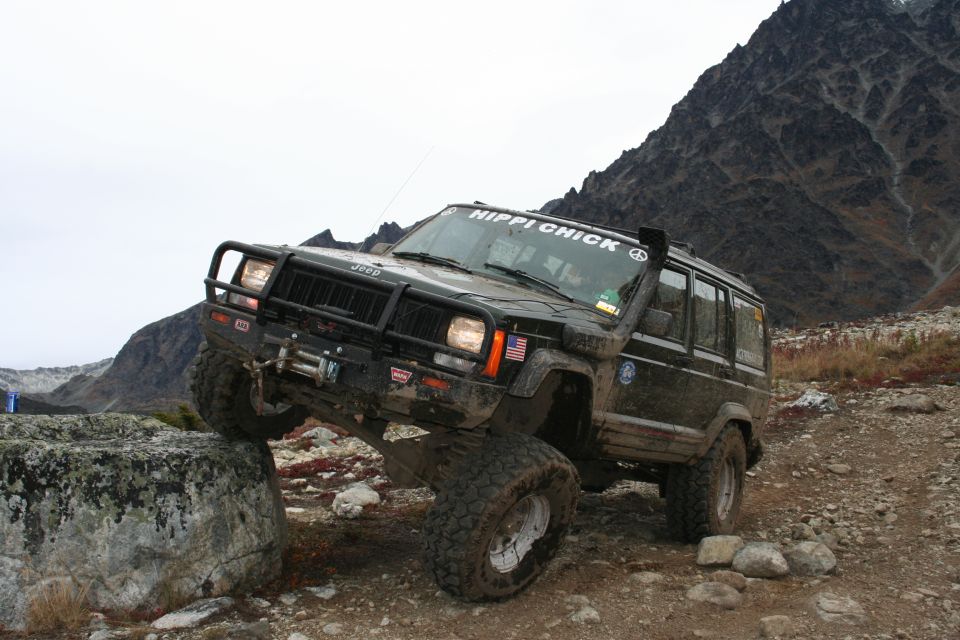 1995 Jeep Cherokee with "HIPPI CHICK" sticker on windshield, lifted, on a rock