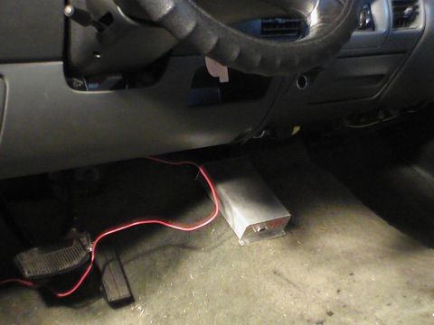 1991 Ford Bronco - The interior of a vehicle shows the dashboard, steering wheel, pedals, and an aftermarket device with red wires.