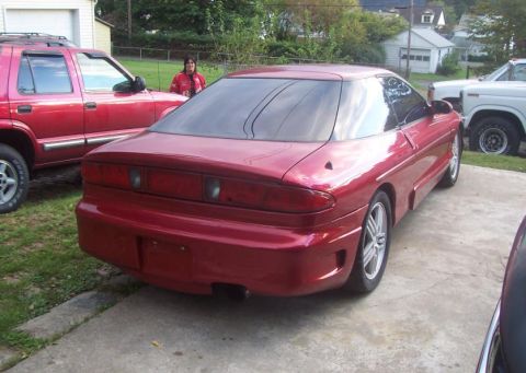 1995 Ford Probe - Rear view of a red coupe, parked outdoors with other vehicles nearby.
