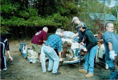 1997 Jeep TJ - Group of men working on the front section of a heavily damaged and dismantled vehicle outdoors.