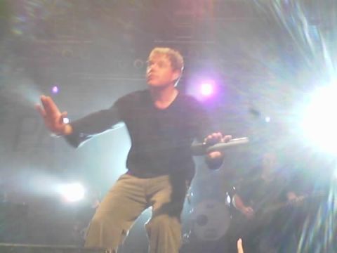 1989 Ford Bronco - A musician performs live on stage, illuminated by bright lights, with band members visible behind him.