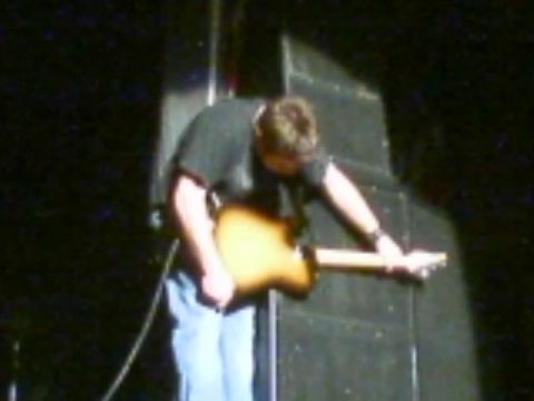 1989 Ford Bronco - A musician is seen playing a guitar on a stage, with a large speaker cabinet behind them.