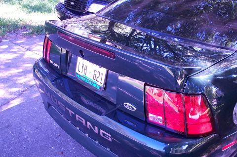 2001 Ford Mustang - The rear of a 2001 Ford Mustang is shown, with its distinctive taillights and 'Mustang' badging visible.