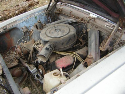 1972 Ford Ranchero - The engine bay of a weathered vehicle is shown with the hood open, revealing a dusty engine and surrounding components.