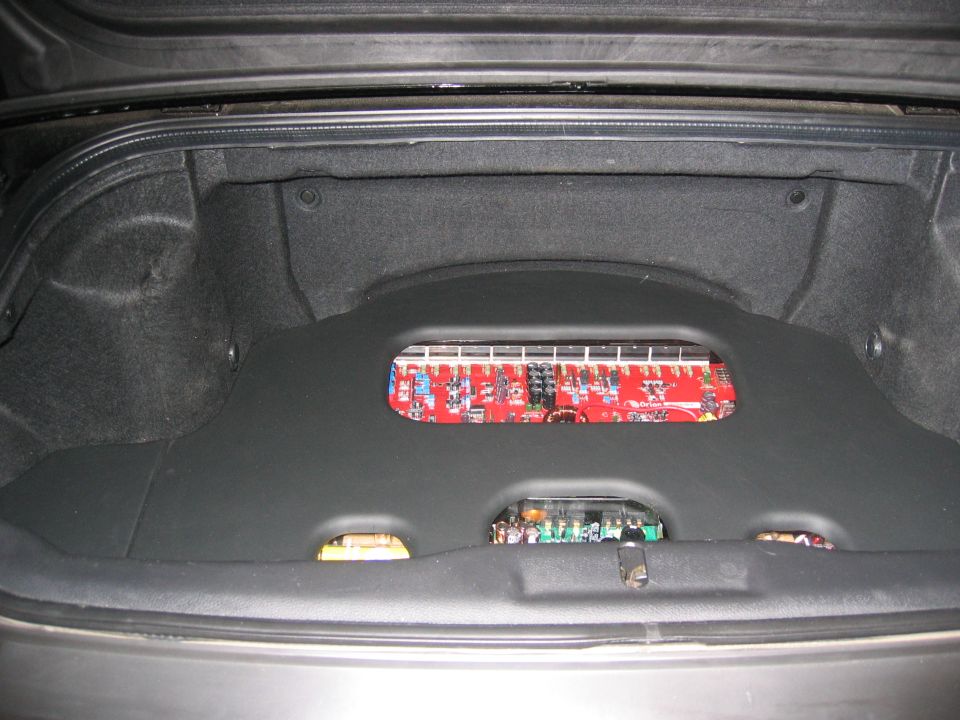 Trunk with custom black panel showing red Orion amplifier board and green circuit board through cutouts
