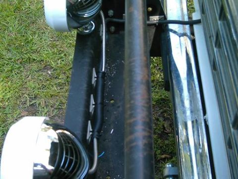 1986 Ford Bronco - This image shows a close-up view of offroad lights attached to the side of a vehicle, with a grassy background.