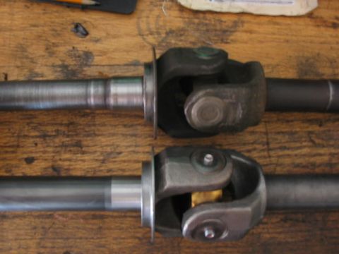 1995 Ford Bronco - Close-up view of two driveshafts and their universal joints resting on a wooden table.